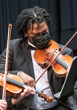 Violinist wearing a mask, violin to chin, bow outstretched