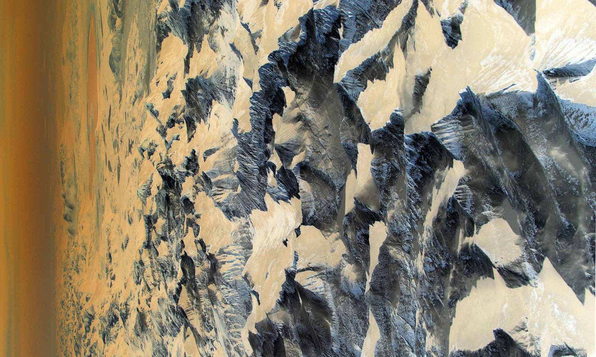 An abstract, aerial-style image shows jagged, mountain-like forms in shades of gray and cream, with textured ridges and shadows fading into a warm-toned gradient along one edge.