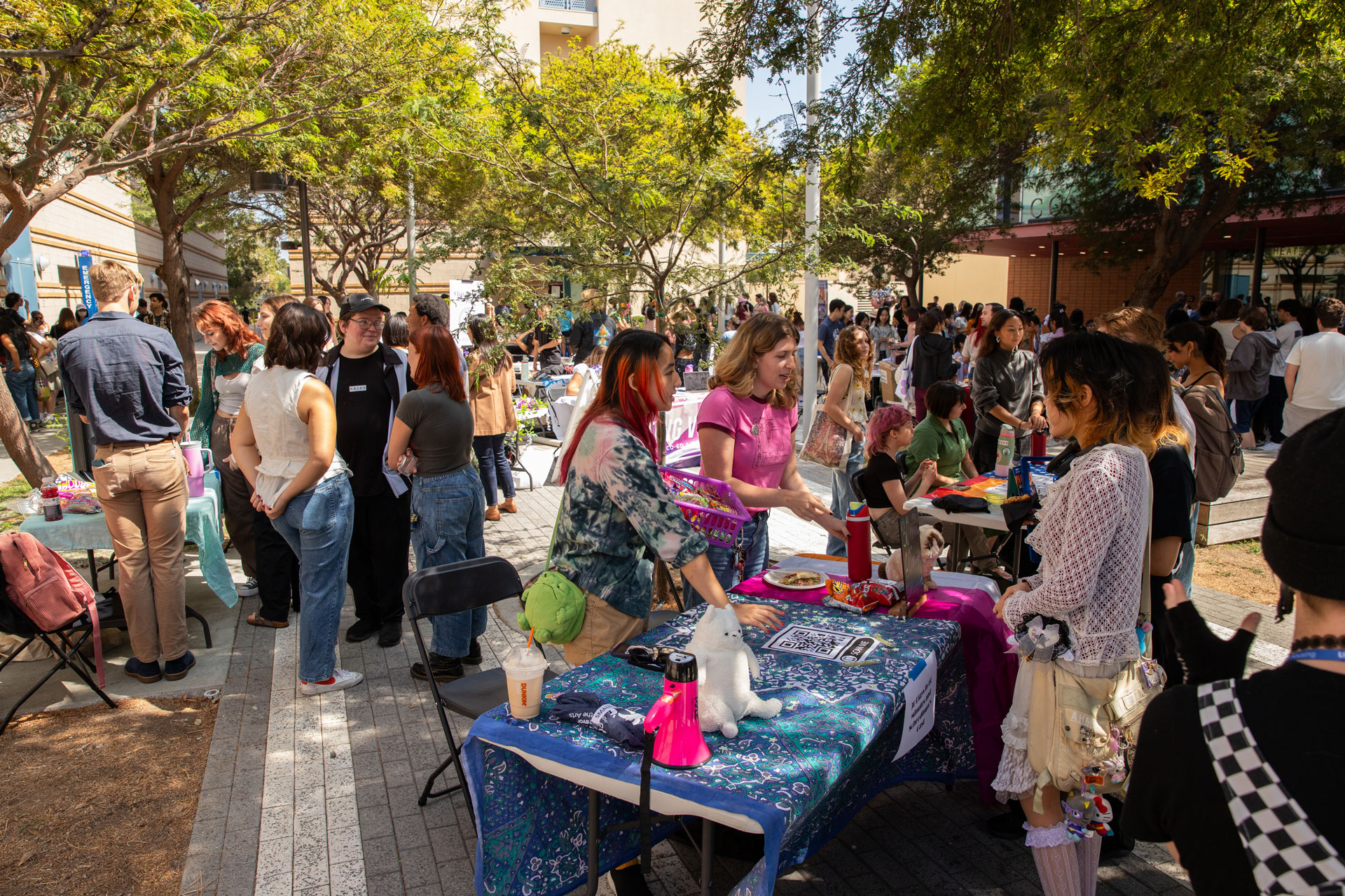 Students at the annual Arts Involvement Fair, exploring tables and activities outdoors among trees.