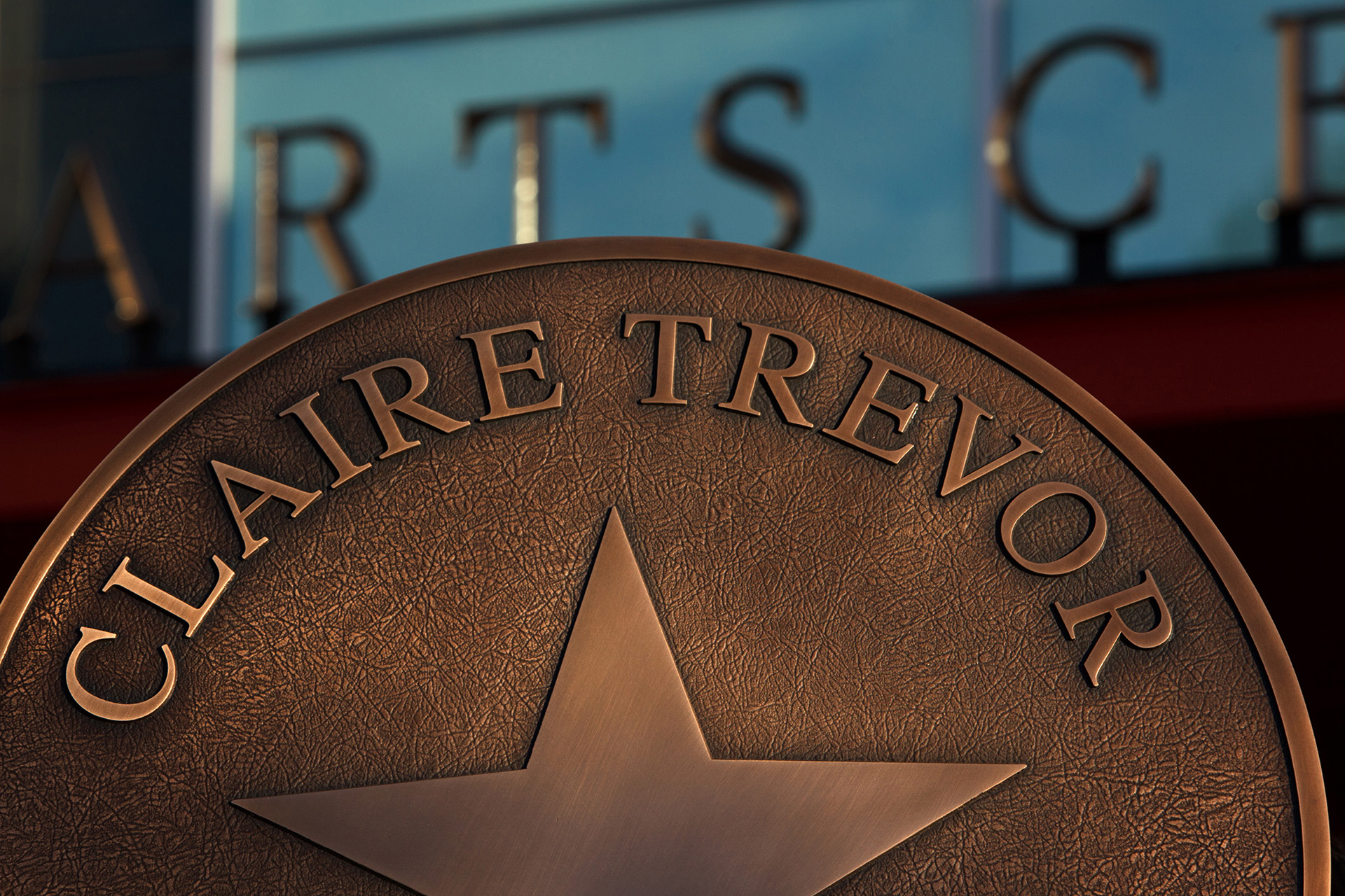 A close-up of the bronze Claire Trevor star at UC Irvine set against a blurred background of the arts campus.