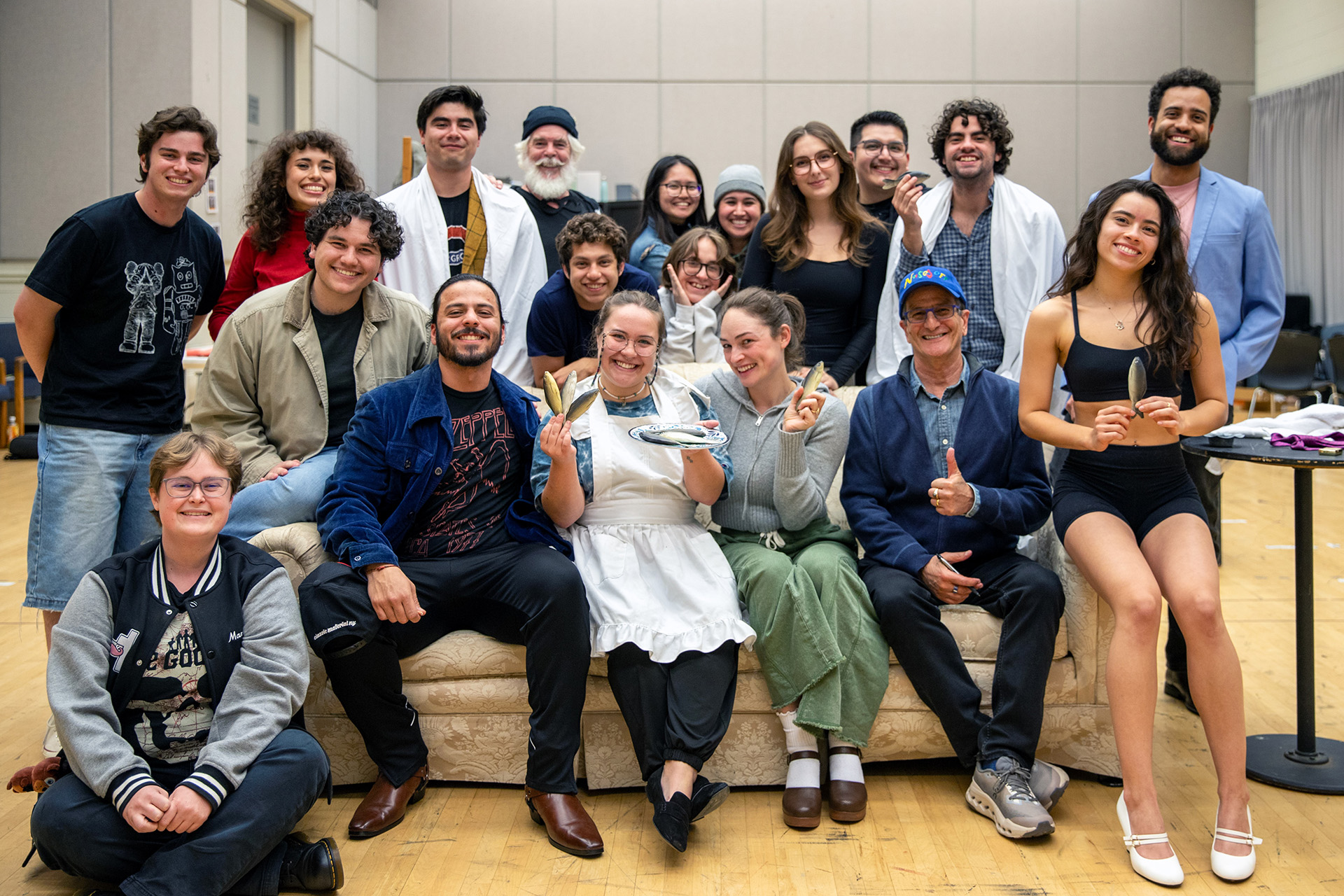 Group of people smiling on a couch in a cast photo