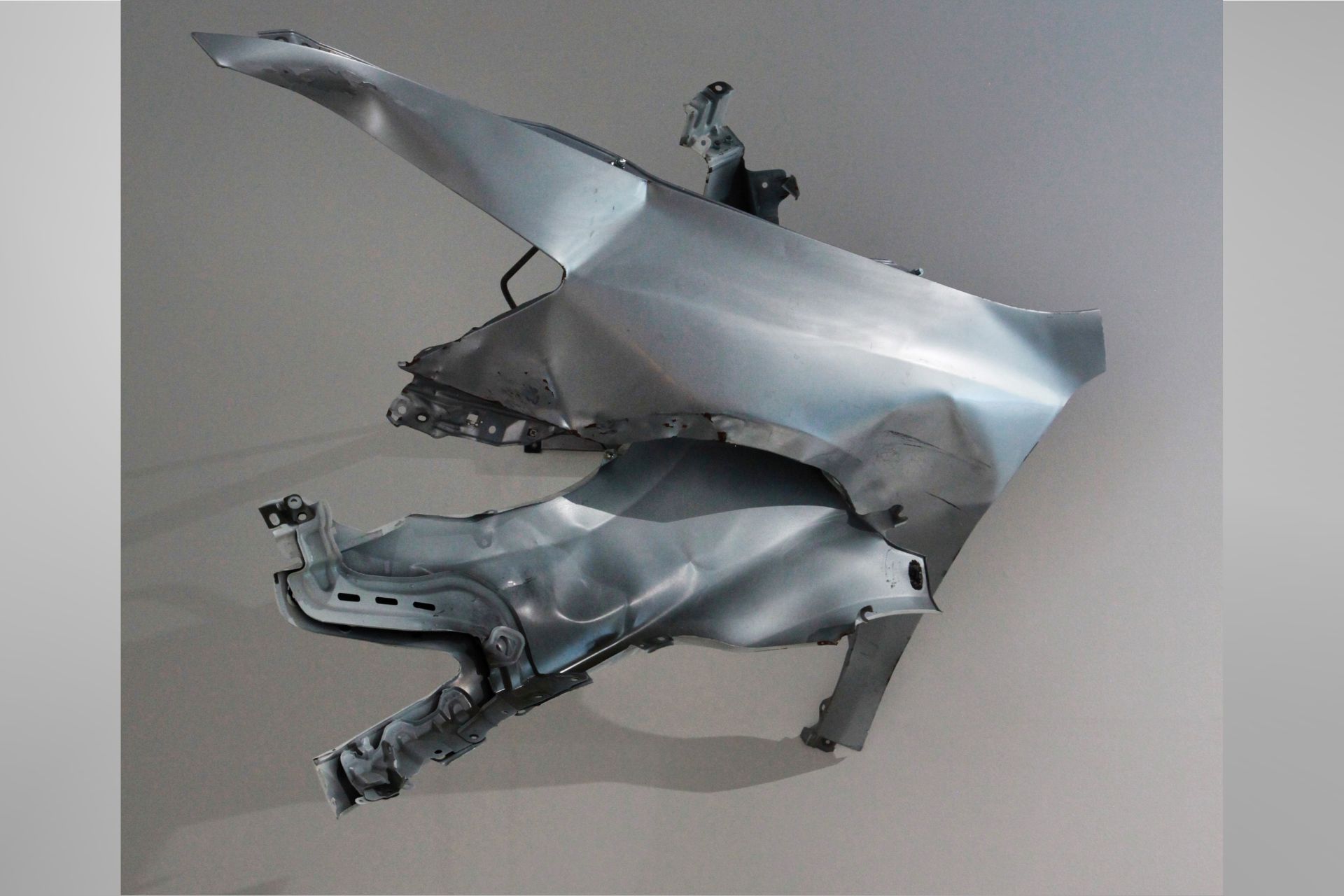 Beatrice Schleyer, Rubber: Wall-mounted sculpture made from curved metallic automotive parts arranged in an abstract, layered form