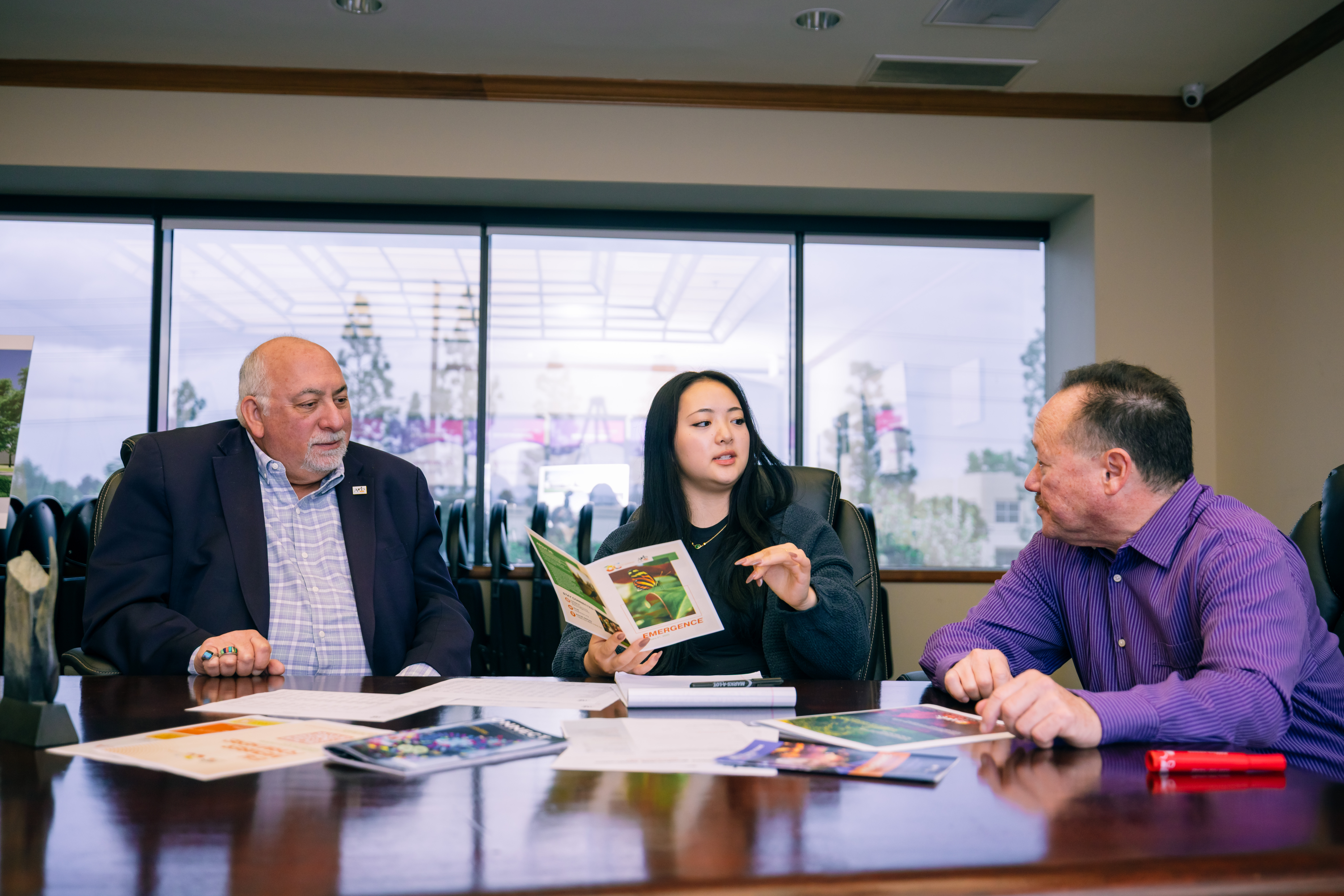 An Arts Launch Intern speaks with two organization leaders at a conference table.