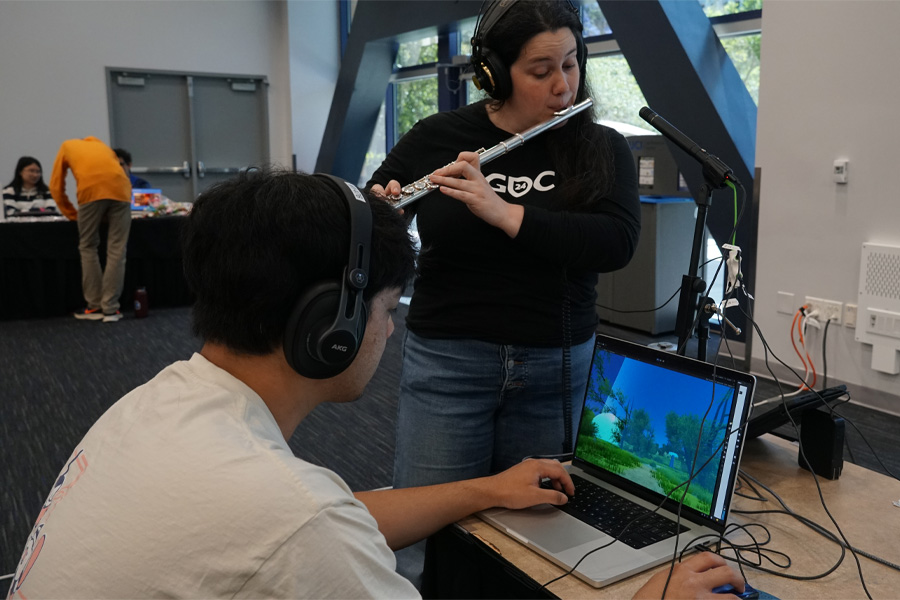 Rebecca Larkin on left playing the flute while her and another person play Duet for Video Game