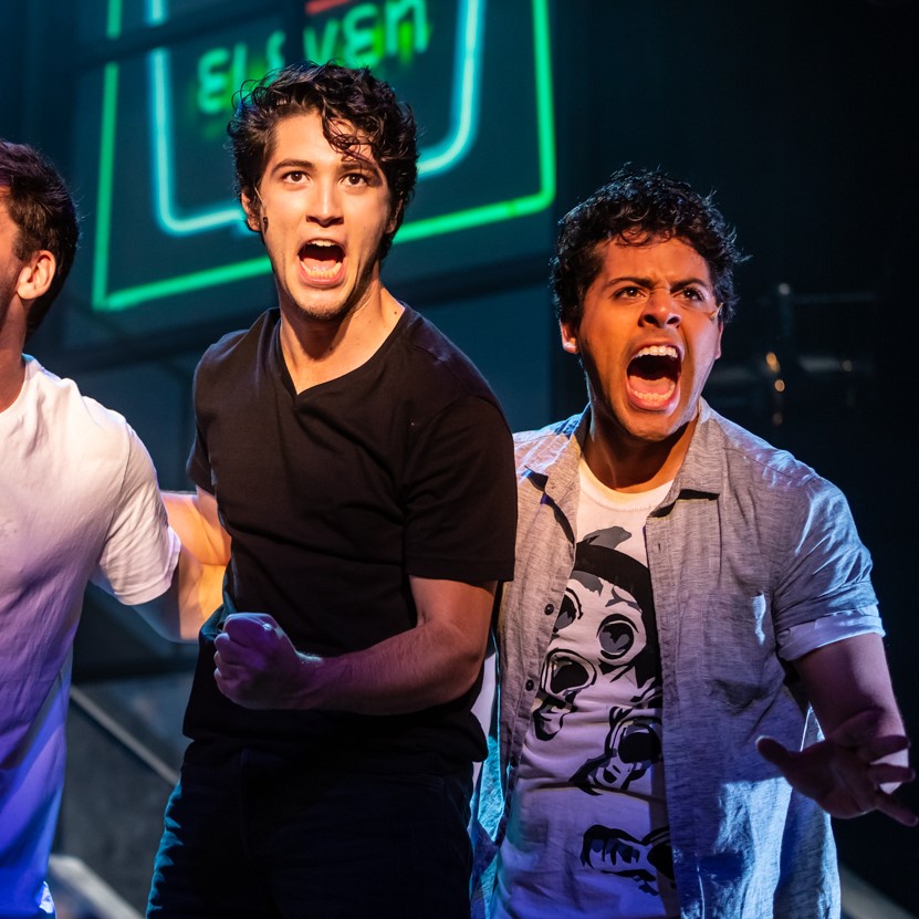 Student actors deliver a high-energy moment during a live UCI Drama performance under stage lighting