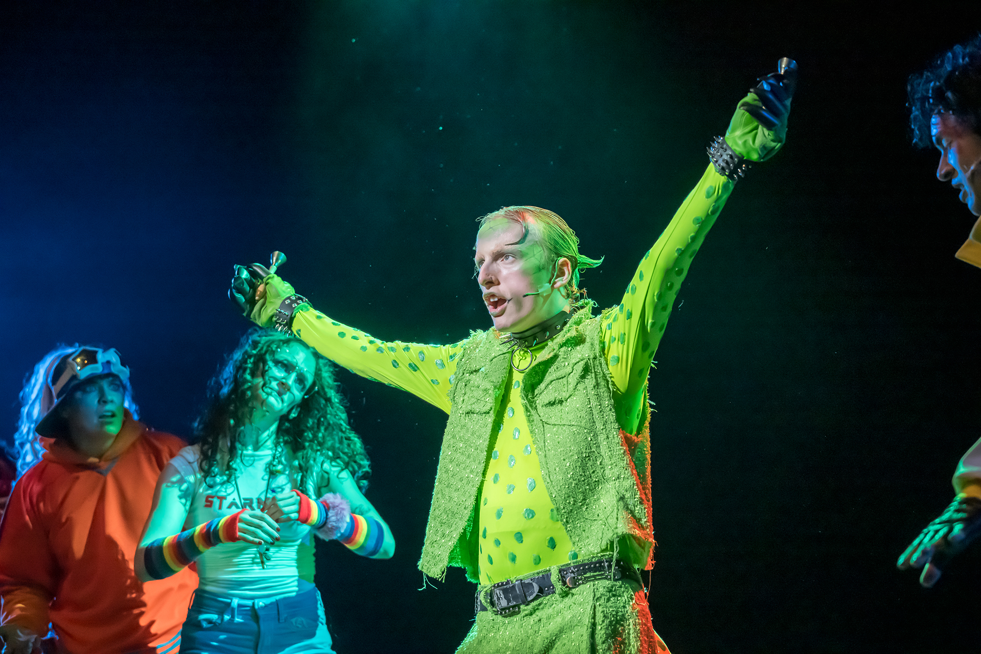 UCI Drama students perform a high-energy musical theatre scene, featuring bold costumes and expressive movement under stage lighting.