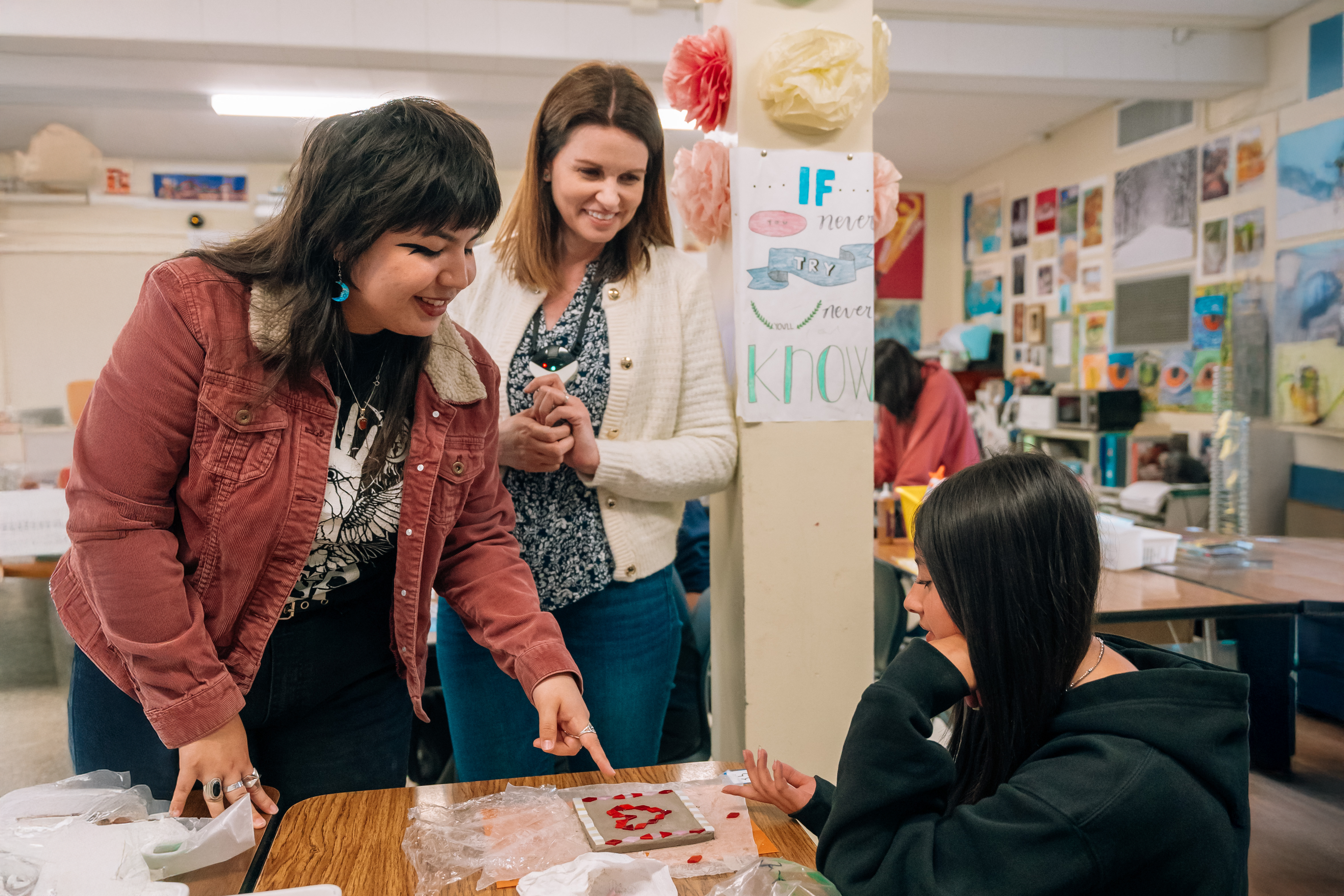 L1100597-2.jpg      Alt Txt: A Creative Connections Teaching Artist Intern and Educator looking at a students’ artwork. 