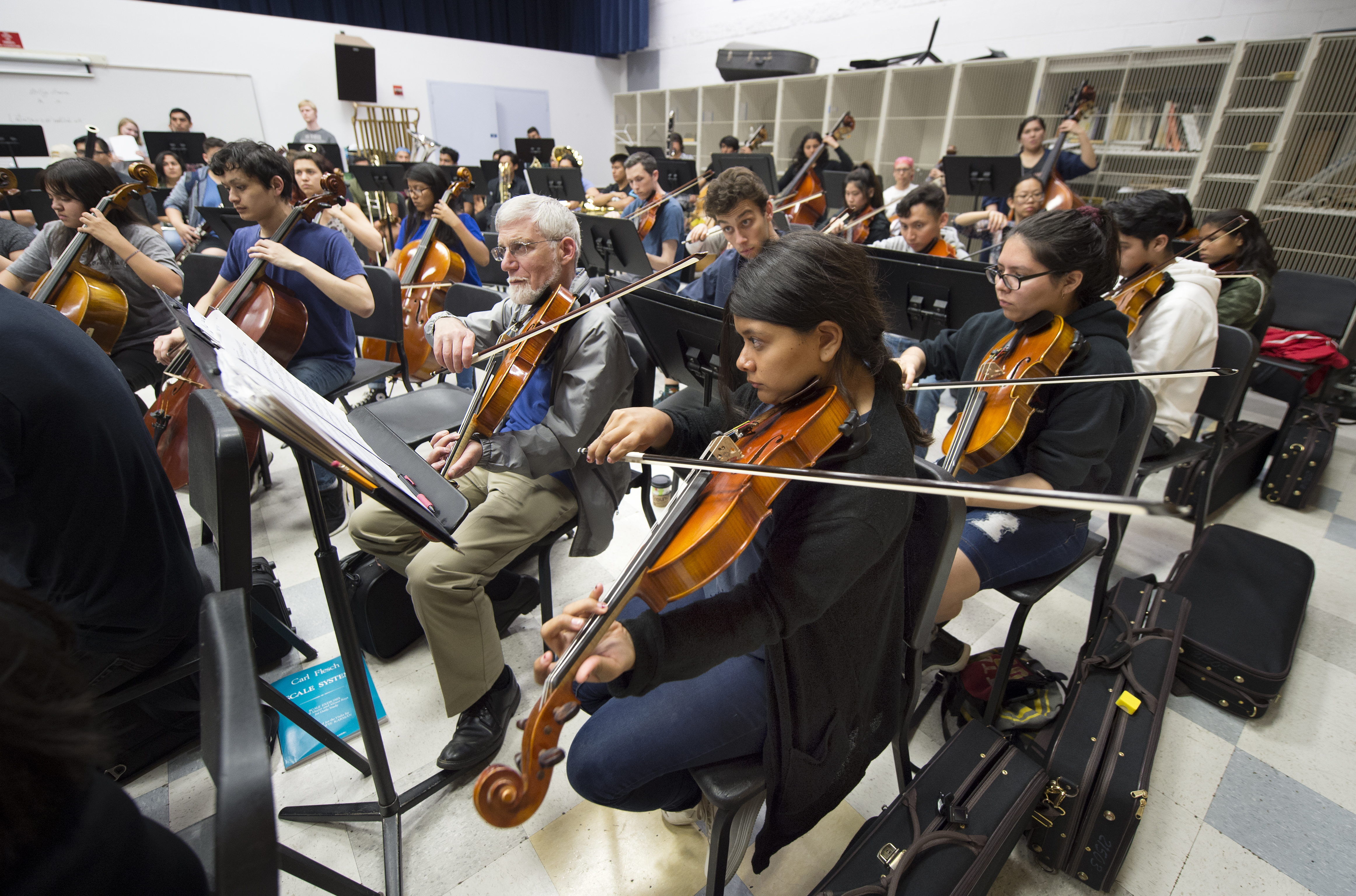 String musicians playing in a combined high school and college symphony orchestra