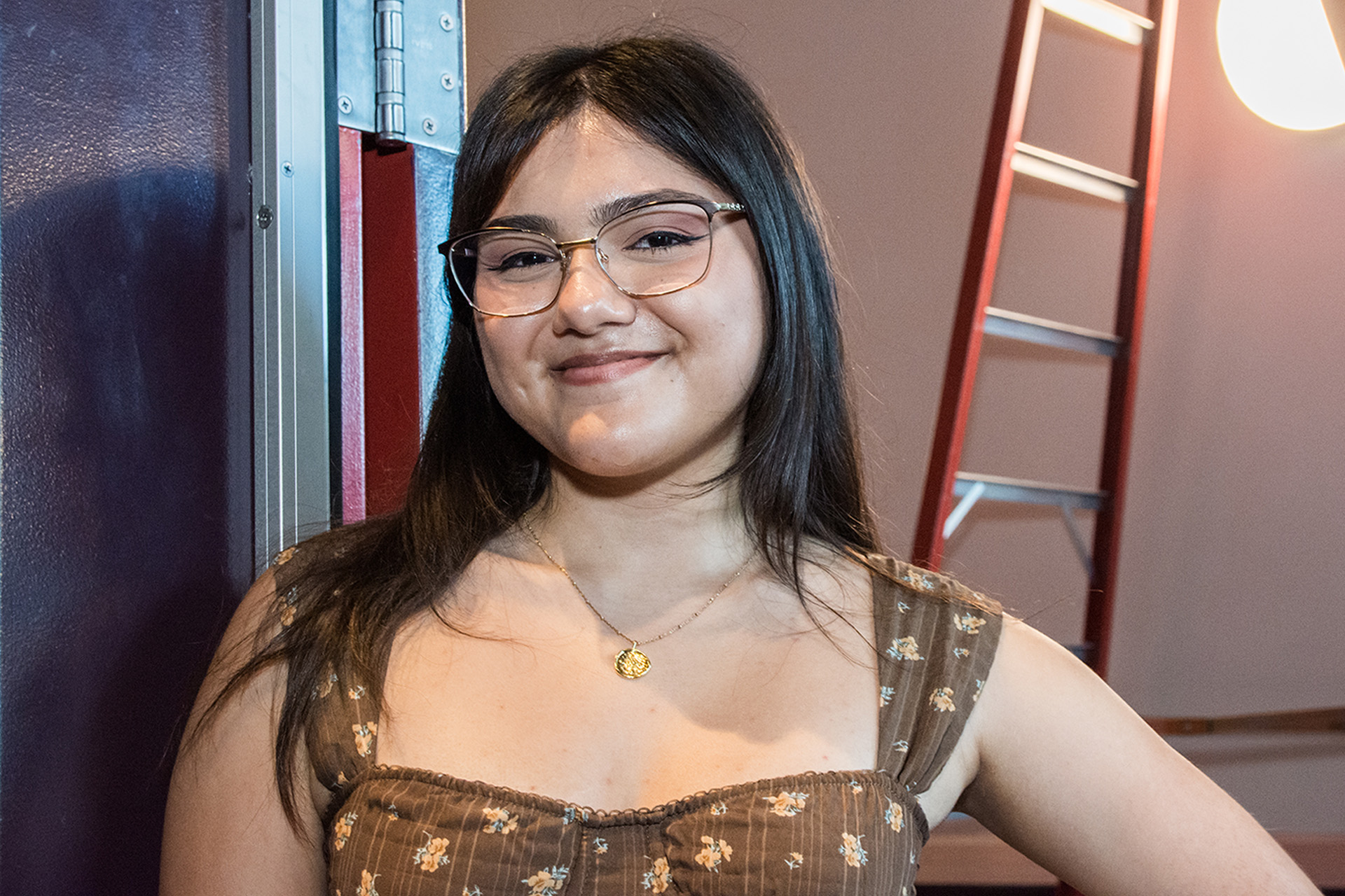 Samantha Mendez smiles backstage near a ladder and stage light during Creative Connections.