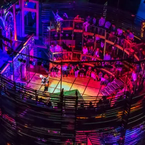 New Swan Shakespeare Festival theater at UC Irvine, with audience encircling the stage during a nighttime performance under colorful lighting