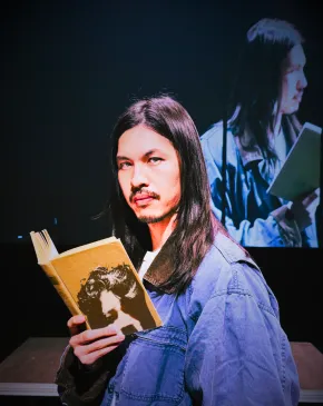 Kurt Kana holding a book in a solo one-act performance