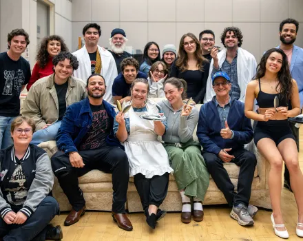Group of people smiling on a couch in a cast photo