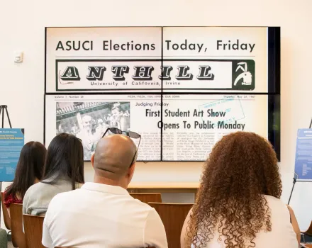 Audience members watch a student experimental film featuring archival images from UC Irvine’s history on a large video wall during the Connecting Histories exhibition.