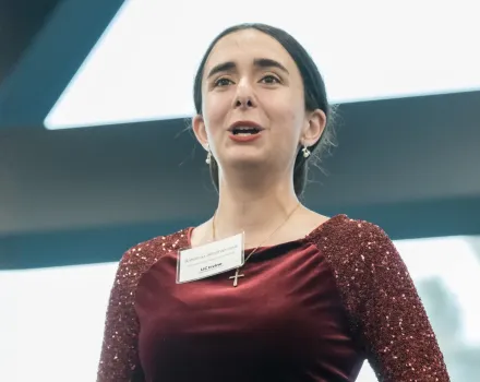 Baharnaz Alimohammadi, the Bette and Steven Warner Music Scholar, is singing, photographed from a low angle against an angular architectural backdrop.
