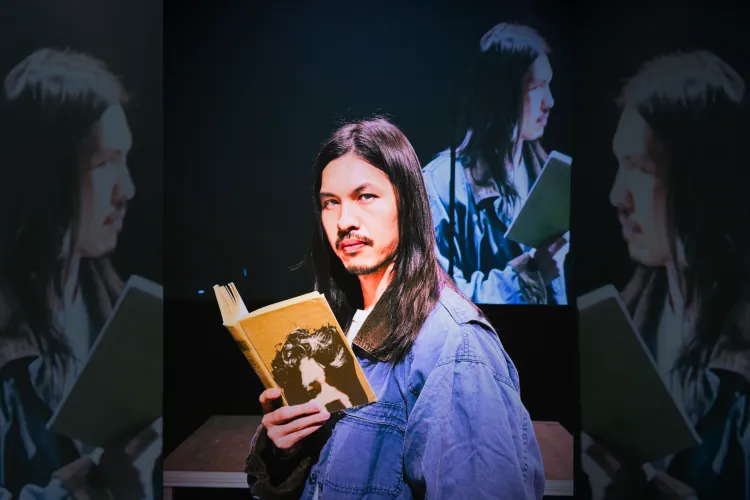Kurt Kana holding a book in a solo one-act performance