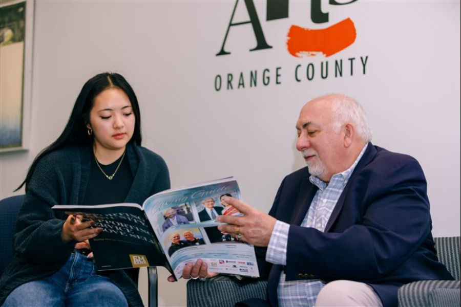 Two people sitting and reviewing a magazine.