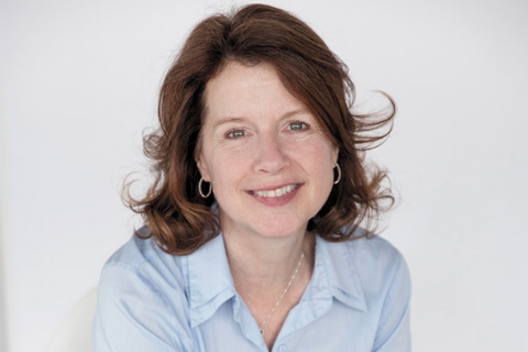 Headshot of smiling woman with brown, shoulder-length hair; wearing a white, buttoned, collared shirt