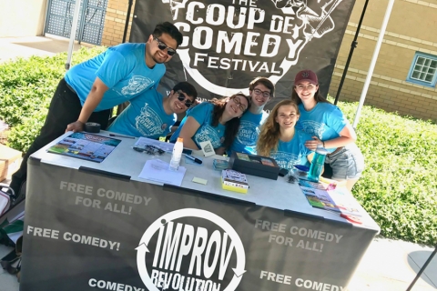 Students sitting smiling behind a table