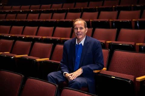 Man in blue suit seated in theatre