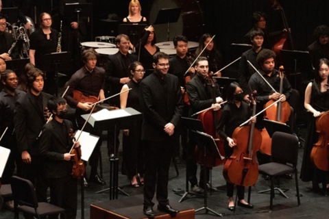 UCI Symphony Orchestra on stage facing audience, taking a bow