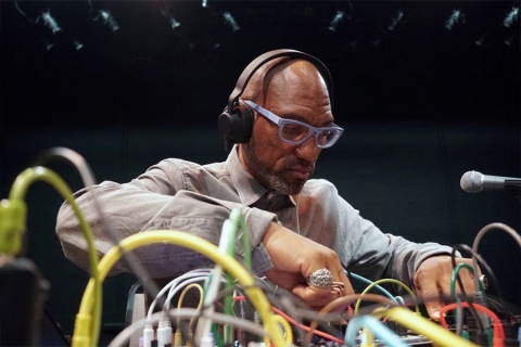 A man with headphones on surrounded by electronics
