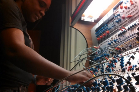 Person standing in front of electronics board with many cables extending from it