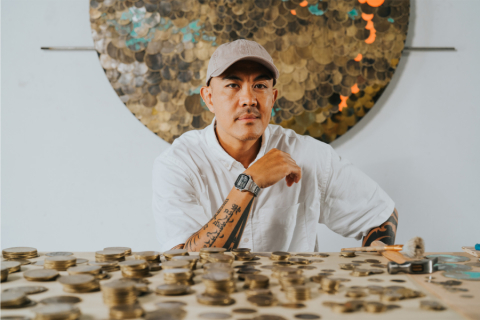 Person leaning against table with coins
