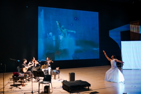 Musicians, a dancer and digital display on stage during a performance