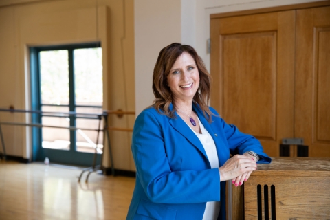 Dr. Kelli Sharp stands in front of a piano in one of the dance studios