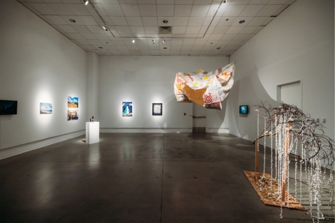 Interior gallery with art, including an installation hangin from the ceiling