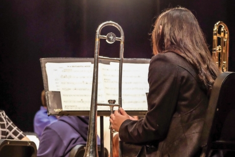 Image of woman holding trombone, her back to camera