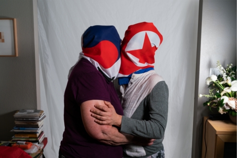 Two people with shrouds over their heads, kissing 
