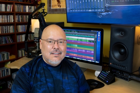 Mile Hooker sits in his home studio in front of a computer screen. 