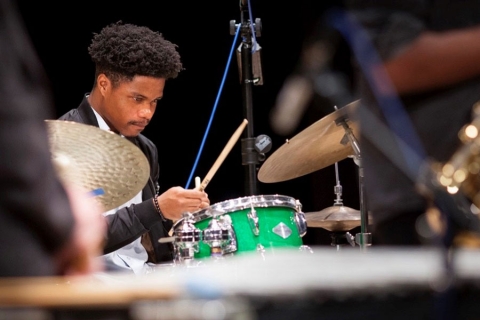 Musician on-stage at drum-set with drumsticks in hand