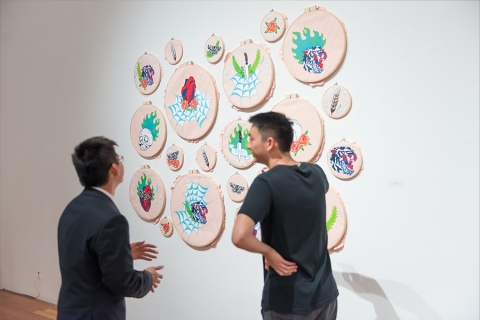 Two people discussing artwork hanging on wall