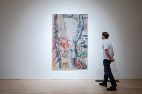 Person standing in front of a hanging piece of art