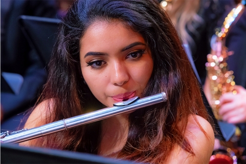 Closeup of woman with long, dark hair playing flute