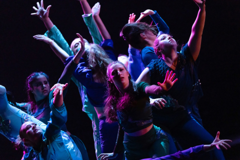 Dancers on stage with arms extended, looking up