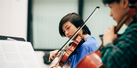 Student with violin to chin, bow mid-air