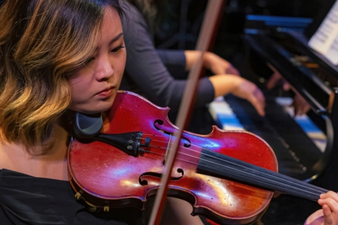 Woman with violin to chin, bow mid-air