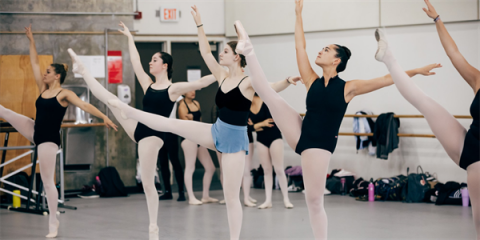 Ballet dance student in class lifting legs into air