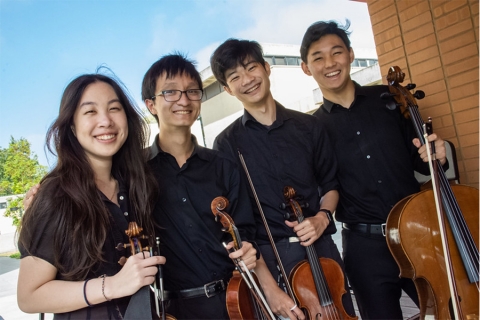 Four student wearing all black, holding violins