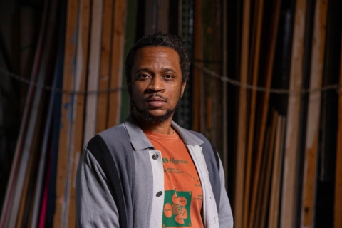 A person standing in front of a wood wall