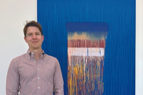 Person in checkered shirt next to blue abstract painting