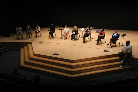 Actors sitting on stage during a reading of a play