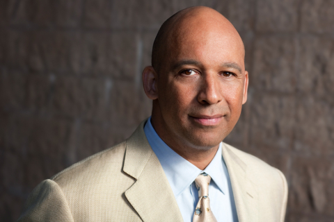 Headshot of person in front of gray brick wall